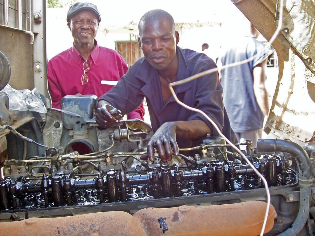Formateur accompagnant un apprenti pendant un travail pratique sur un moteur