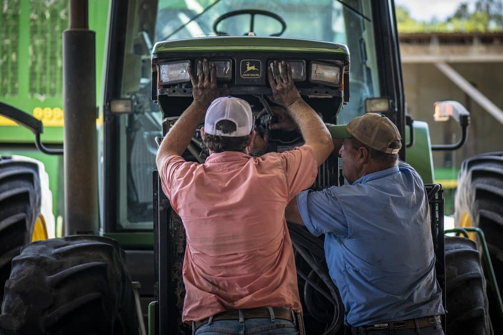 Deux mécaniciens intervenant sur le moteur d'un tracteur
